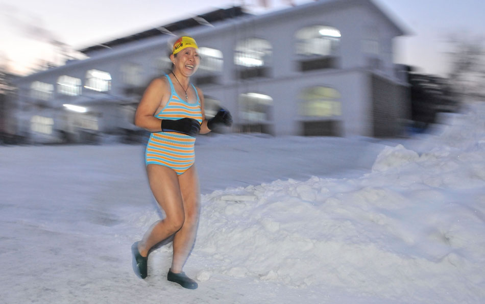 A woman is doing warm-up exercise before jumping into the icy water in Changchun, capital city of northeast China’s Jilin province, Dec. 18, 2012. (Xinhua/Wu Haofei)