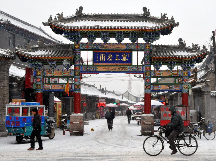 Citizens walk past a street amid snow in Hohhot, capital of north China's Inner Mongolia Autonomous Region, Dec. 20, 2012. A heavy snow hit Inner Mongolia on Thursday, bringing a big temperature drop and winds to the region.(Xinhua/Liu Yide)