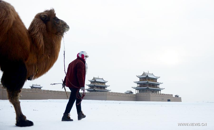 A woman walks with a camel beside the Jiayu Pass after snowfall in Jiayuguan City, northwest China's Gansu Province, Dec. 21, 2012. (Xinhua/Zhang Meng) 