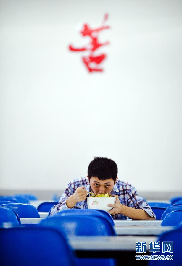 A student named Shi Ke has lunch in a classroom in Changsha, capital of central China’s Hunan Province on May 24, 2012. He studied for one more year in high school in order to enter a better college. Although Gao Kao (entrance examination for college) is not the only way to success in China, most people still expect to change their fate through the precious opportunity. (XInhua/Bai Yu)