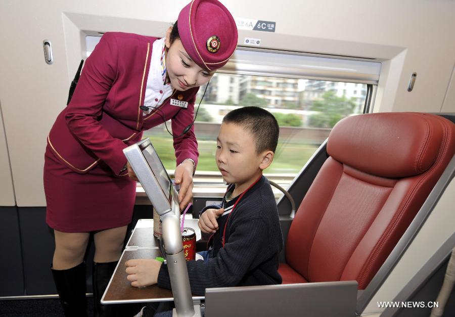 A stewardess adjusts a television set for a child in a business class carriage of G80 express train during a trip to Beijing, capital of China, Dec. 22, 2012.