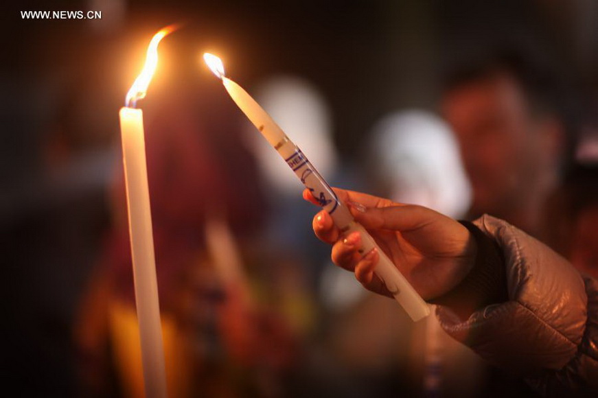 A worshiper lights a candle in the Church of the Nativity, traditionally believed to be the birthplace of Jesus Christ, as she attends the Christmas celebrations in the West Bank biblical town of Bethlehem on Dec. 24, 2012. (Xinhua/Fadi Arouri)