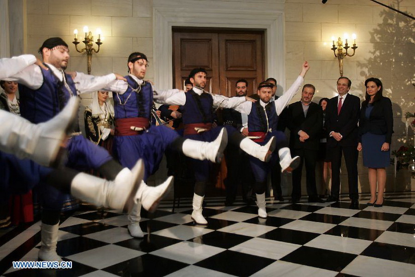 Members of cultural clubs, dressed in traditional costumes, perform for Greek Prime Minister Antonis Samaras (2nd R) at Maximos Mansion, central Athens, Greece, Dec. 24, 2012. On Christmas Eve, traditional carols are sung throughout Greece, giving a tone of optimism in a country struck by the economic crisis. (Xinhua/Marios Lolos)