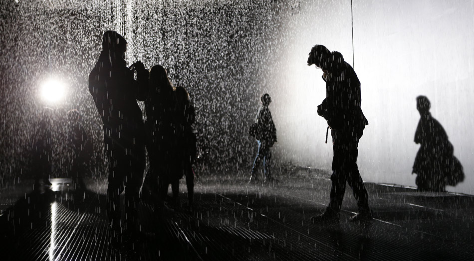 People go to the “rain room” to enjoy the controlled rain in Barbican centre in London, Britain, Dec. 17, 2012. The installation in the ceiling can locate the audience and control the area above their heads not to rain, once the audiences enter the 100 square meters raining area. The rain room will be open to the public on March 3, 2013. (Xinhua/Wang Lili)