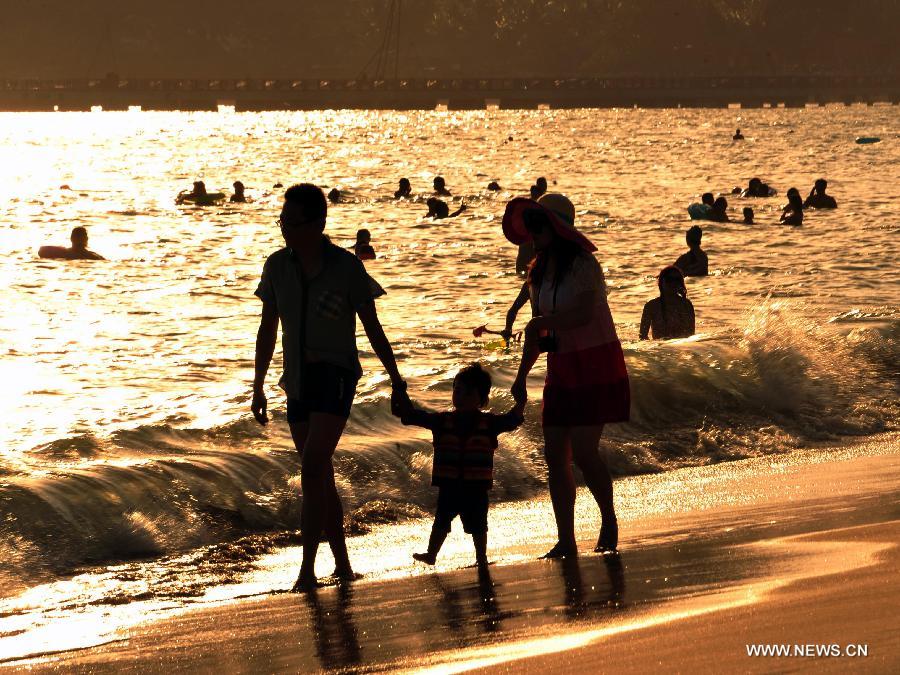 Tourists enjoy themselves at a beach in Sanya, a popular winter toursim destination in south China's Hainan Province, Dec. 27, 2012. (Xinhua/Hou Jiansen)