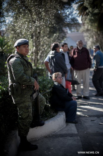 A Mexican Army soldier stands guard at a site where weapons are exchanged for groceries and cash by residents as part of "For your family, voluntary disarmament" program held at Iztapalapa Deputation, in Mexico City, capital of Mexico, on Dec. 27, 2012. (Xinhua/Pedro Mera)  