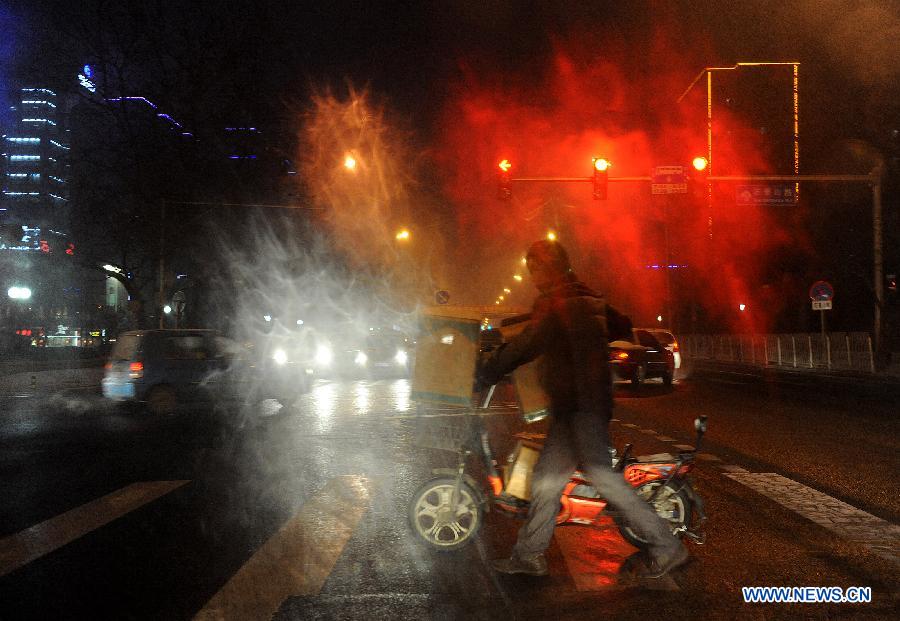 A local citizen pushes his electric bicycle to cross the Changchunjie crossing in snow in Beijing, capital of China, Dec. 28, 2012. Beijing has witnessed the 7th snowfall in this winter on Friday. (Xinhua/He Junchang)