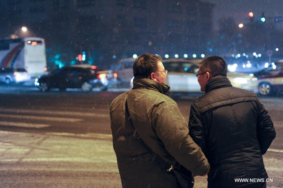 Two men wait for taxi in snow near the Heping Gate in Beijing, capital of China, Dec. 28, 2012. Beijing has witnessed the 7th snowfall in this winter on Friday. (Xinhua/Sun Ruibo)