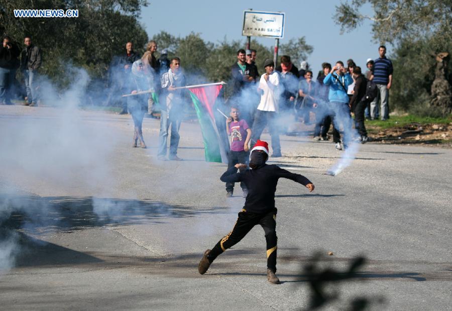 A Palestinian protester throws stones at Israeli soldiers during a protest against the expanding of Jewish settlement in the West Bank village of Nabi Saleh, near Ramallah, on Dec. 28, 2012. (Xinhua/Fadi Arouri) 