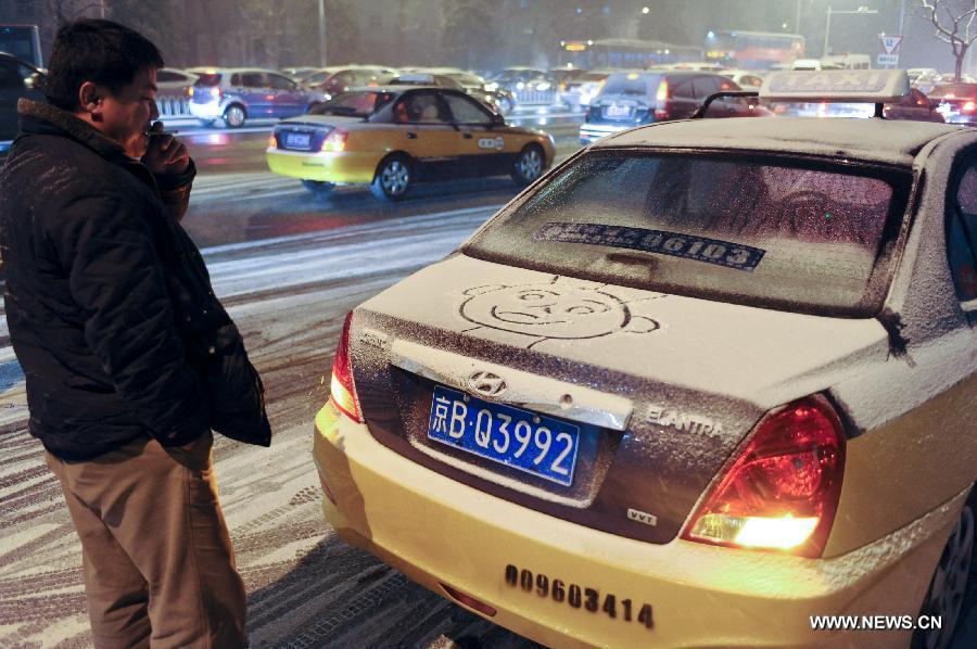A taxi driver looks at his "snow painting" on his car near Xuanwu Gate in Beijing, capital of China, Dec. 28, 2012. Beijing has witnessed the 7th snowfall in this winter on Friday. (Xinhua/Sun Ruibo)