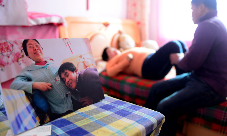 Lu Yuanfang lies in bed and her husband massages her mussels before the departure to Beijing on Dec. 24, 2012.  Lu, 31, from Lanzhou of Gansu province, has been paralyzed since she was very young suffering from the spinal muscular atrophy. She married with Luo Zhongmu in May 2011 and is seveb months pregnant. Accompanied by her mother and husband, Lu took a train to Beijing to have a cesarean section operation on Dec. 24, 2012. (Xinhua/Zhang Meng)