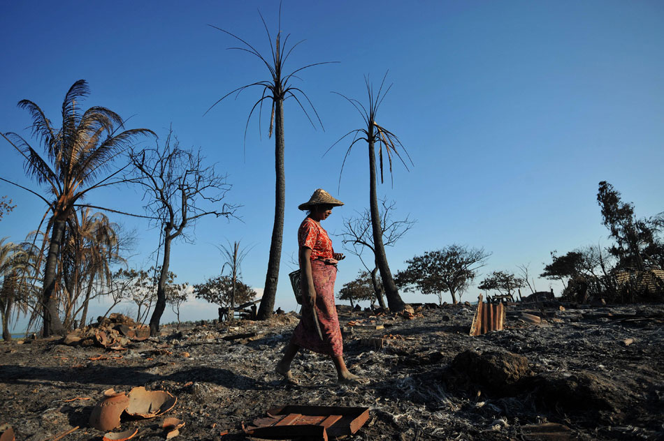 A woman walks past the debris of houses that were burn down in the outskirt of Sittwe, capital city of Myanmar's western state of Rakhine, on Oct. 27. A week-long renewed riot in Rakhine killed at least 84, official media reported on Oct. 29. (Xinhua/AFP)