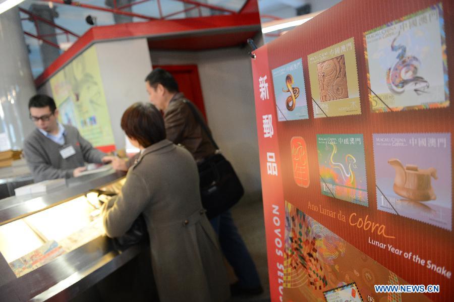 Citizens select the stamps featuring a cartoon snake at a post office in Macao, south China, Jan. 3, 2013. (Xinhua/Cheong Kam Ka) 