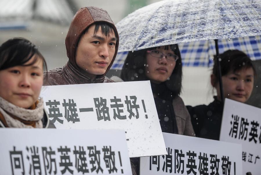 People hold slogans to show their respects to the deceased firefighters who lost lives in a rescue operation on Jan. 1 at the Hangzhou Yusei Machinery Co., Ltd in Hangzhou, capital of east China's Zhejiang Province, Jan. 4, 2013. (Xinhua/Han Chuanhao) 