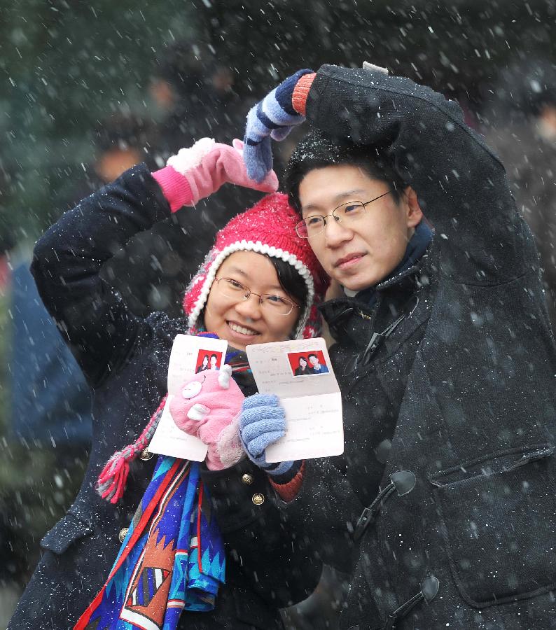 A couple showing their marriage certificates pose for a photo after registering in the marriage registration office in Changsha, capital of central China's Hunan Province, Jan. 4, 2013. Quite a number of couples flocked to tie the knot on Jan. 4, 2013, or 2013/1/4, which sounds like "Love you forever" in Chinese. (Xinhua/Li Ga) 