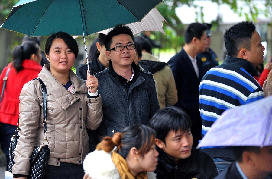 Couples wait in rain to register in front of the marriage registration office in Haikou, capital of south China's Hainan Province, Jan. 4, 2013. Quite a number of couples flocked to tie the knot on Jan. 4, 2013, or 2013/1/4, which sounds like "Love you forever" in Chinese. (Xinhua/Guo Cheng)