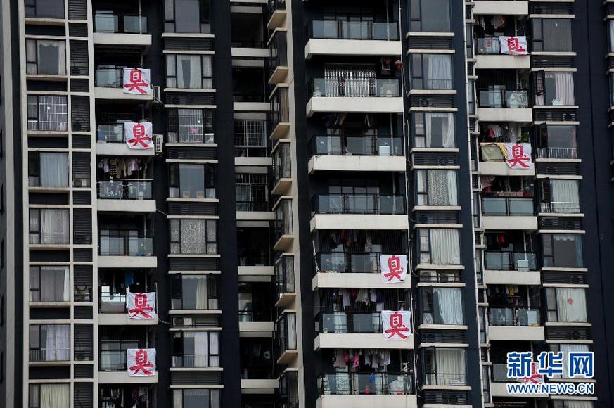 House owners hang banners from their balconies to attract government department’s attention to the pollution that annoys them in a neighborhood in Nanning, Guangxi in July 2012. Since 2009, the residents have been suffering stinky smelling and floating dust pollution caused by the garbage dumping site, piggery and medical garbage. (Xinhua/Huang Xiaobang)