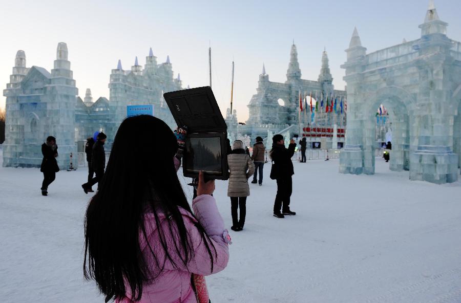 Visitors pose for photo by an ice sculpture in the Ice and Snow World during the 29th Harbin International Ice and Snow Festival in Harbin, capital of northeast China's Heilongjiang Province, Jan. 5, 2013. The festival kicked off on Saturday. (Xinhua/Wang Jianwei)