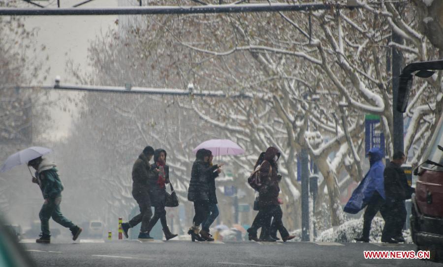 Citizens walk across the street in snow in Ji'an County, east China's Zhejiang Province, Jan. 4, 2013. Zhejiang Weather Bureau on Friday issued the first orange alert for road icing after the heavy snow and freezing weather since Thursday. (Xinhua/Xu Yu) 