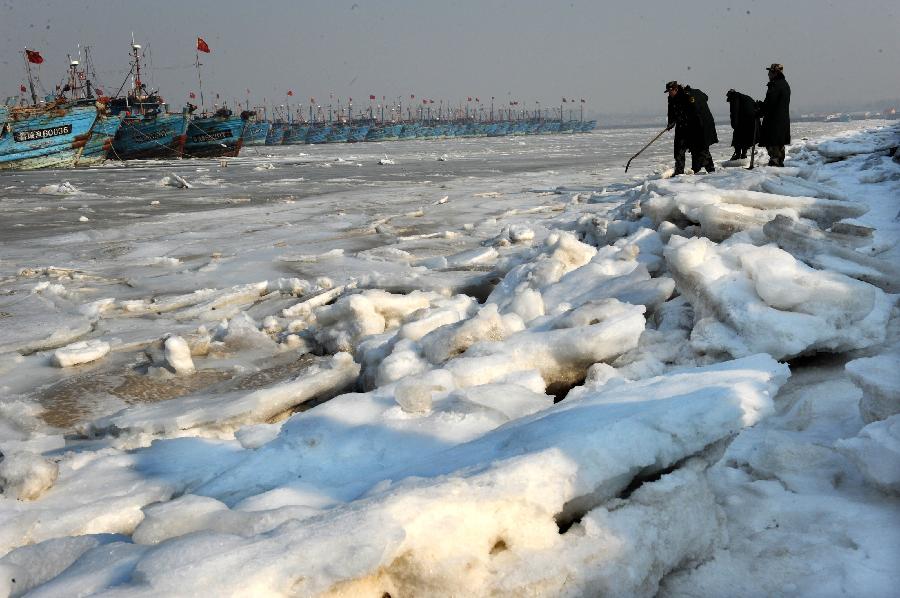 Policemen examine ice condition at Xidayang Fishing Wharf in Qingdao, east China's Shandong Province, Jan. 5, 2013. The ice conditions in the Bohai Sea and the Yellow Sea this January may be more serious than that in the past years, forecasted by North China Sea Marine Forecasting Center of State Oceanic Administration. (Xinhua/Li Ziheng)