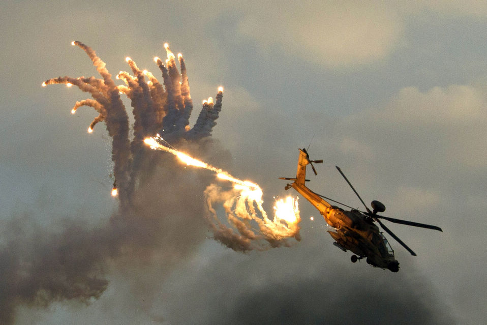 An Israeli Boeing AH-64 Apache longbow helicopter releases anti-missile flares during an air show conducted at the graduation ceremony of Israeli pilots at the Hatzerim air force base in the Negev desert, Israel, on Dec. 27, 2012. (Xinhua/AFP)