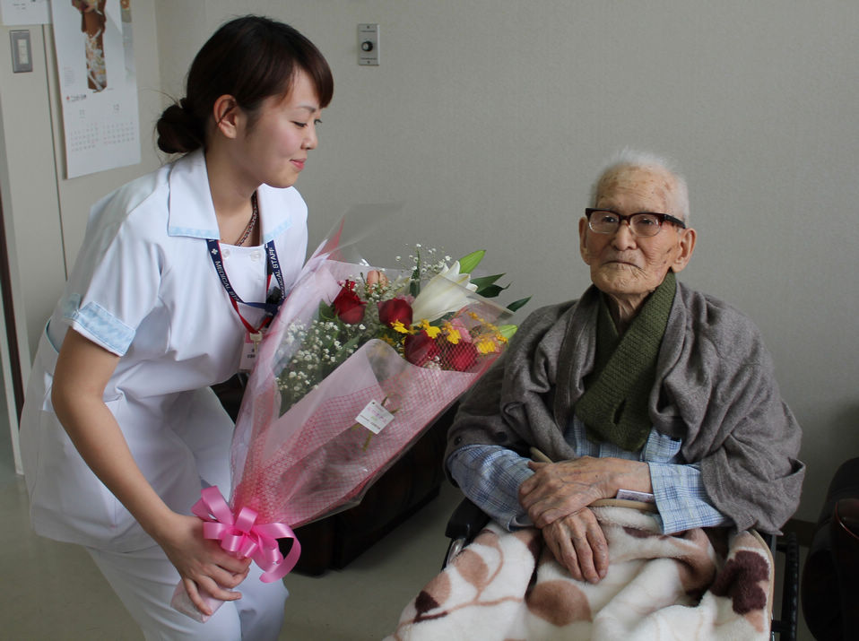 This picture taken by the Kyotango City Government shows 115-year-old man Jiroemon Kimura receiving a flower bouquet from a nurse at a hospital in Kyotango, Kyoto prefecture in western Japan.(Xinhua/AFP)