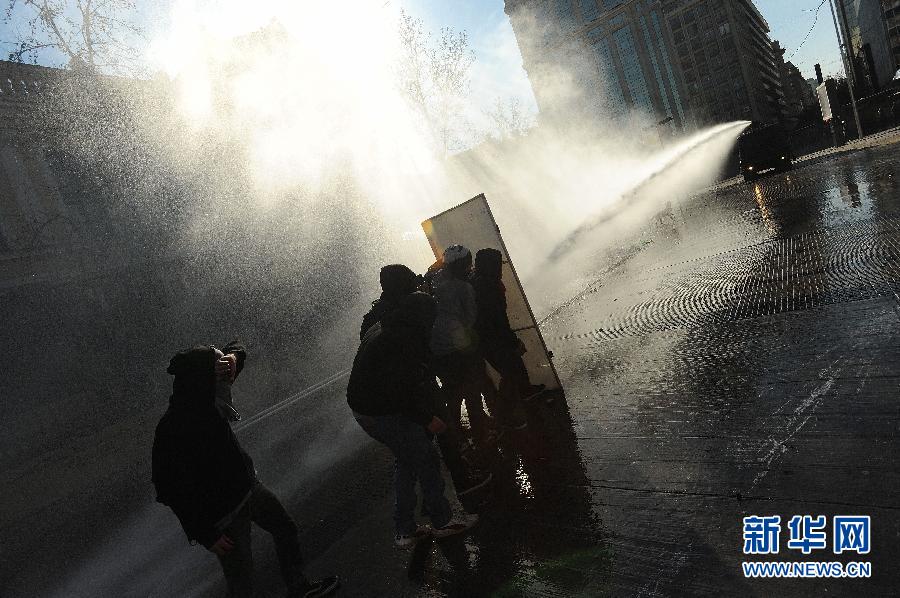 Protestors keep themselves away from police’s water gun in Santiago, Chile, Aug. 25, 2012. (Photo/Xinhua)