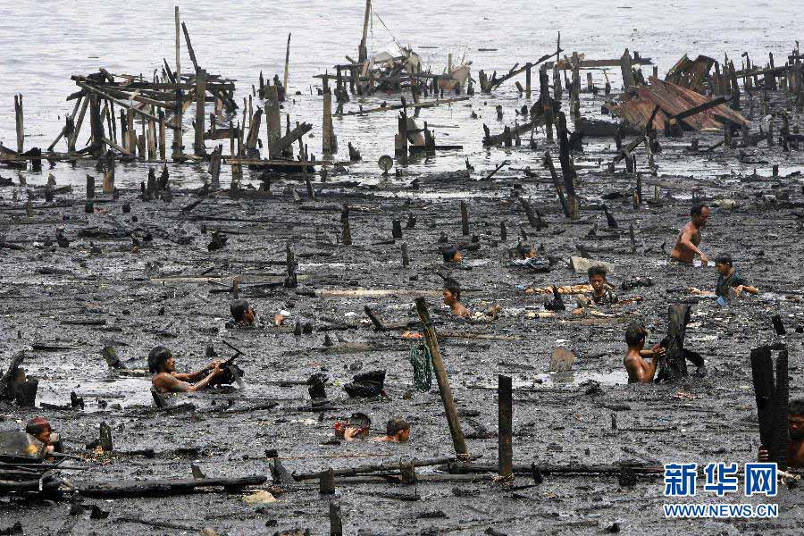 Residents look for recyclable goods in the ruins after the big fire, which made more than 10,000 local people lose their homes, in a gutter in Manila, Philippines, May 15, 2012. (Xinhua/Rouelle Umali)