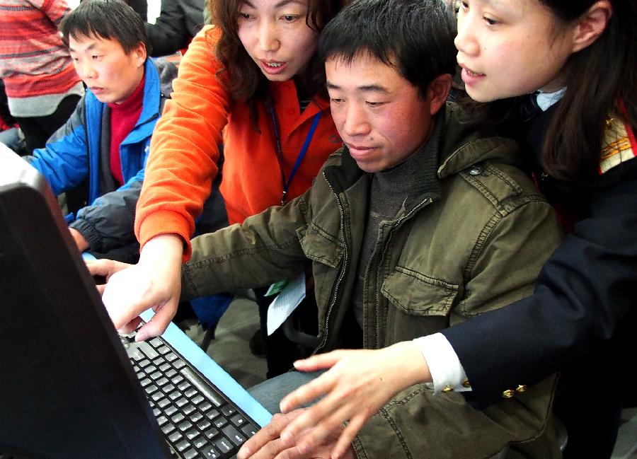 Wu Shiming (2nd R), a migrant worker buys tickets on line under the guidance of working staff in east China's Shanghai Municipality, Jan. 7, 2013. The tickets for the upcoming Spring Festival rush period can be purchased via online and phone-call booking systems since Jan. 7. Shanghai railway administration provided group ticket-purchasing service for migrant workers in Shanghai. The Spring Festival for family reunions begins from the first day of the first month of the traditional Chinese lunar calendar, or Feb. 10, 2013. (Xinhua/Chen Fei)