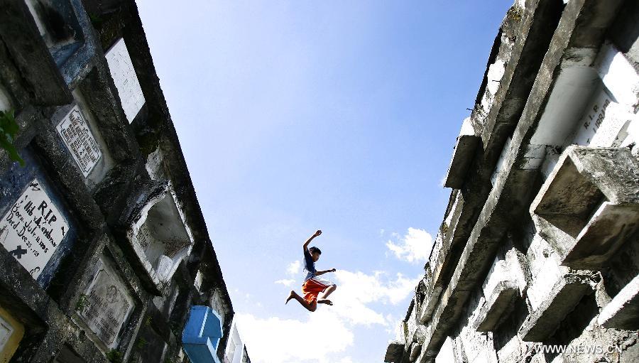 A boy jumps above a cemetery in Valenzuela, the Philippines, on Oct. 29, 2012. (Xinhua/Rouelle Umali) 