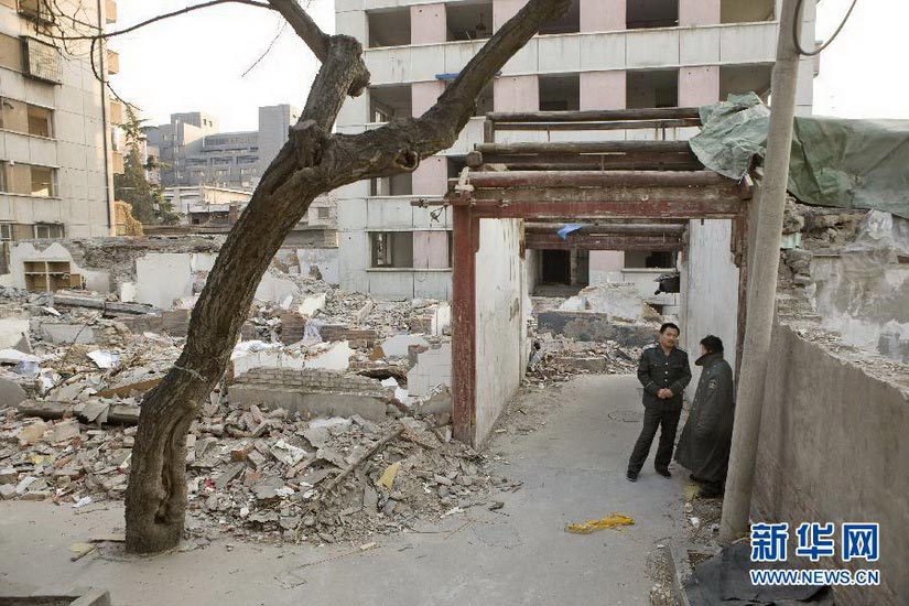 Security guards chat outside of the demolished former residence of Chinese architecture masters Liang Sicheng and Ling Weiyin in Zongbu alley, Beijing, Jan. 27, 2013. The demolition of former residences of celebrities by real estate developers has caused controversy in society. (Xinhua/Shen Bohan)