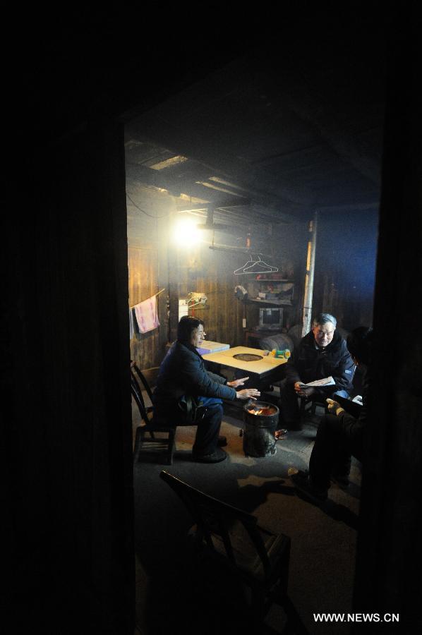 Postman Zhang Meichong (L) takes a rest at local villager Zhang Yunsong's home in Enshi, central China's Hubei Province, Dec. 23, 2012. Equipped with a stick and two bags, Zhang Meichong, a village postman, has been working in the mountainous area for 15 years and traveled a distance about 180,000 kilometers these years. (Xinhua/Hao Tongqian) 