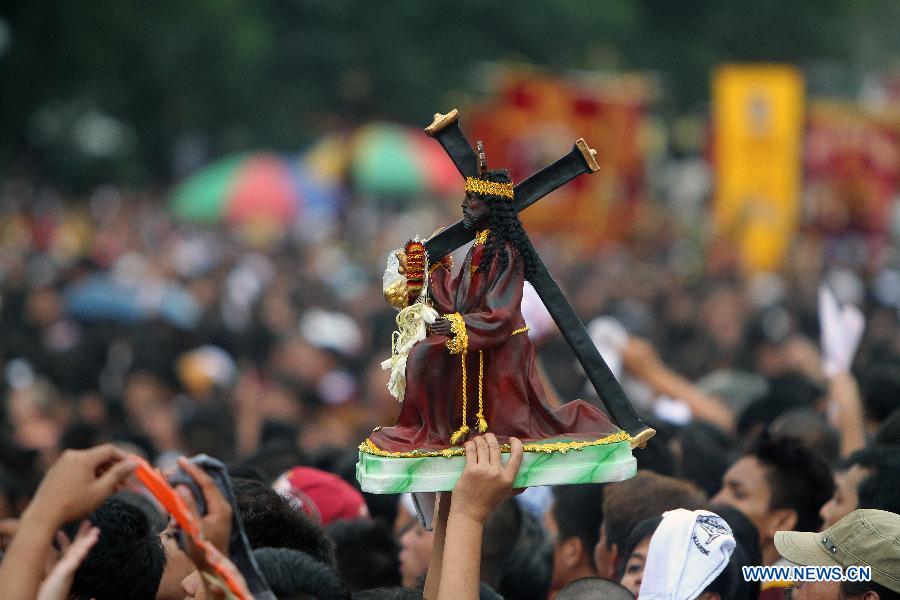 A devotee raises a miniature statue of the Black Nazarene during the annual feast of the Black Nazarene in Manila, the Philippines, Jan. 9, 2013. The Black Nazarene, a life-size wooden statue of Jesus Christ carved in Mexico and brought to the Philippines in the 17th century, is believed to have healing powers in this country. Authorities said about 500,000 people participated in the procession that started in Manila's Rizal Park. (Xinhua/Rouelle Umali)