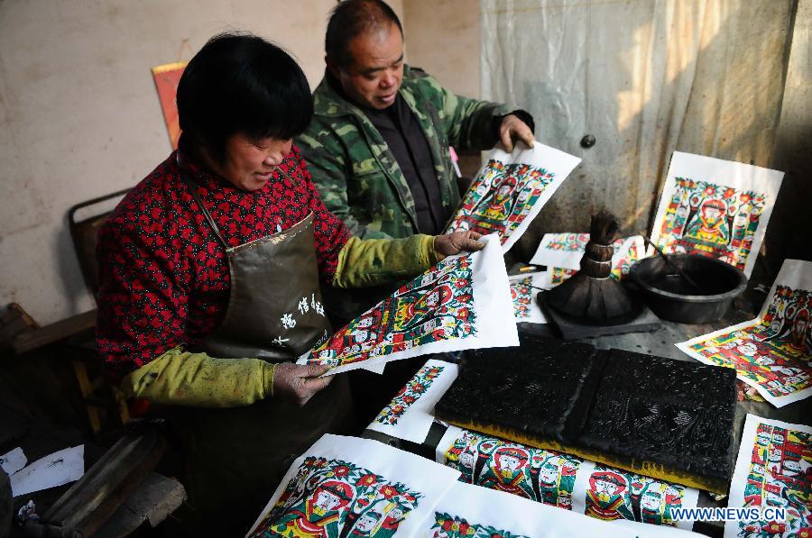 Craftsman Zhai Ruichen (R) and his wife Liu Shufang examine New Year pictures they paints in Liaocheng, east China's Shandong Province, Jan. 9, 2013. The couple were busy painting New Year pictures recently to meet the demand in local market for the Spring Festival in February. (Xinhua/Zhang Zhenxiang)