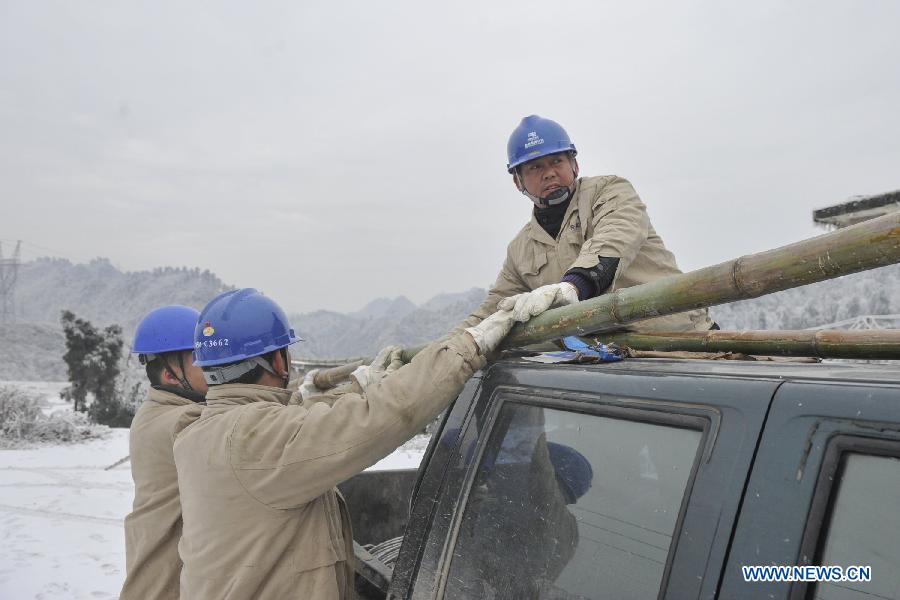 Workers put a bamboo stick on car in Yongsha Village of Shuangliu Township in Kaiyang County, southwest China's Guiyang, Jan. 10, 2013. Local power grid company sent workers to clean power lines which couldn't melt the ice with automatic equipment. (Xinhua/Ou Dongqu) 