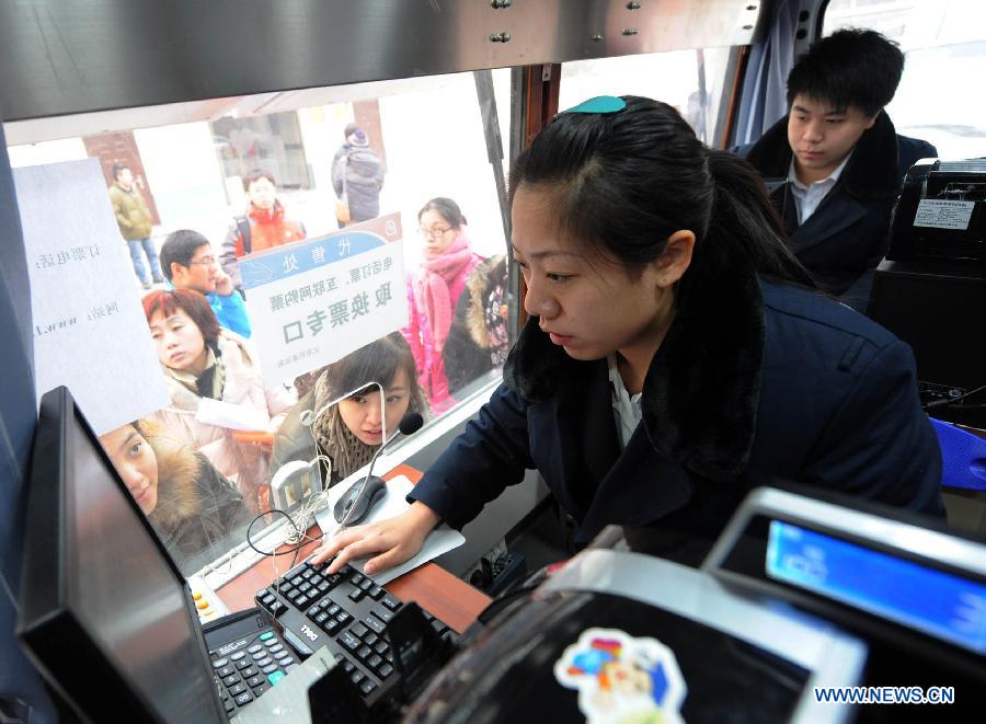 People buy train tickets at a mobile ticket office in Beijing, capital of China, Jan. 11, 2013. Two vehicles were parked in the Chaoyang District on Friday to facilitate people's purchase of train tickets. (Xinhua/Li Wen)