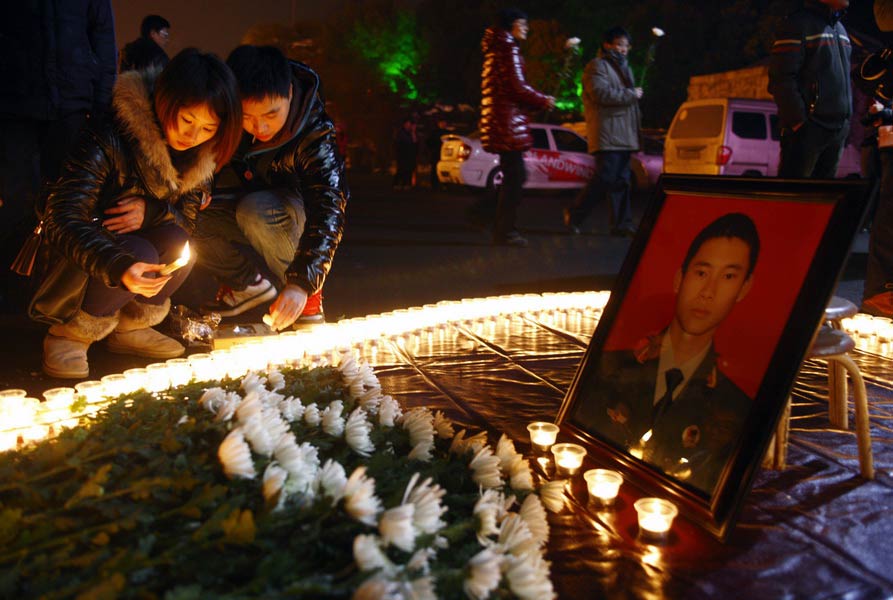 Two citizens light candles beside the portrait of a fire fighter to mourn him on Jan. 7, 2013. Three fire fighters died in a fire disaster in Xiaoshan, Hangzhou. (Xinhua/Cui Xinyu)