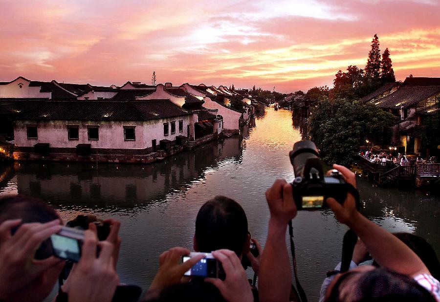 Visitors take photos of sunset glow in Wuzhen, an ancient town in Tongxiang City, east China's Zhejiang Province, July 18, 2009. (Xinhua/Wang Song) 