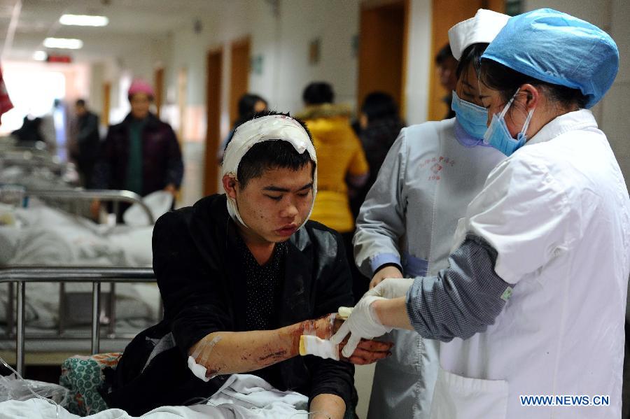 Two nurse bandage up a man's hand injured in an accident on an express way in Xifeng county, southwest China's Guizhou Province, Jan. 13, 2013. Five people died and 19 others were injured after a coach collided with a guardrail and rolled over around 5 a.m. Sunday. (Xinhua) 