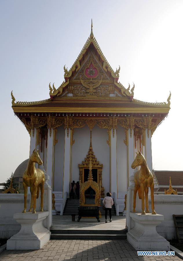 Photo taken on Dec. 31, 2012 shows a tourist visiting the Thai-style Buddha hall of the Baima Temple, or the White Horse Temple, in Luoyang City, Central China's Henan Province. Visitors can see Buddha halls with different styles of foreign countries at the Baima Temple, the oldest Buddhist temple in China.(Xinhua/Li Bo) 