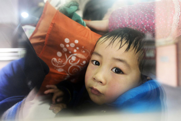 A child looks out from a window seat on the train before it leaves Hangzhou railway station in East China's Zhejiang province, on Jan 15, 2013. Hangzhou railway station is expected to transport around 34 million people during the approaching Spring Festival travel rush, which is still more than 10 days away.(Photo/Xinhua)