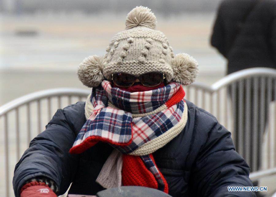 A citizen who wraps up in thick clothers travels on the road in Zhengzhou, capital of central China's Henan Province, Jan. 16, 2013. Affected by a cold front, the haze which has lingered in most parts of Henan for the past two weeks will begin to disperse on Jan. 17, according to the meteorological authority. (Xinhua/Wang Song)