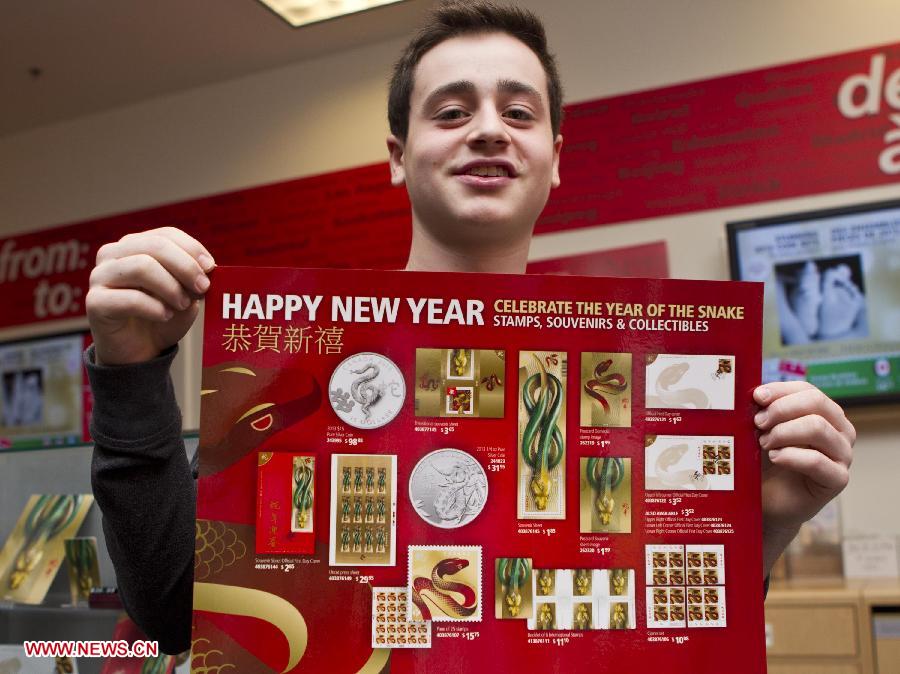 A boy shows a poster including all stamps and collectibles of the Year of the Snake at a post office in Toronto, Canada, Jan. 8, 2013. Canada Post issued the Year of the Snake domestic and international rate stamps and collectibles on Tuesday in celebration of the Chinese Lunar Year of the Snake starting from Feb. 10. The stamps were designed by Joseph Gault and Avi Dunkelman. (Xinhua/Zou Zheng)