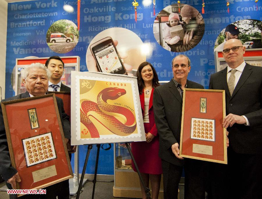 Designers Joseph Gault (1st R), Avi Dunkelman (2nd R) and calligraphist Tan Chaochang (1st L) pose for photos at a post office in Toronto, Canada, Jan. 8, 2013. Canada Post issued the Year of the Snake domestic and international rate stamps and collectibles on Tuesday in celebration of the Chinese Lunar Year of the Snake starting from Feb. 10. The stamps were designed by Joseph Gault and Avi Dunkelman. (Xinhua/Zou Zheng)