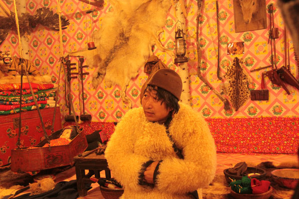 This photo on December 20, 2012, shows a man dressed in a rural folk costume in a house made of snow, which contains a collection of local rural furniture, daily articles and hunting products in Harbin, northeast China's Heilongjiang Province. (CRIENGLISH.com)