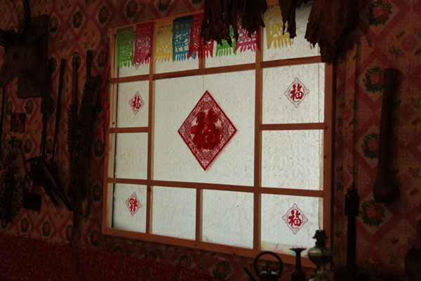 This photo on December 20, 2012, shows paper-cuts on a window of a house made of snow, which contains a collection of local rural furniture, daily articles and hunting products in Harbin, Northeast China's Heilongjiang Province. (CRIENGLISH.com)