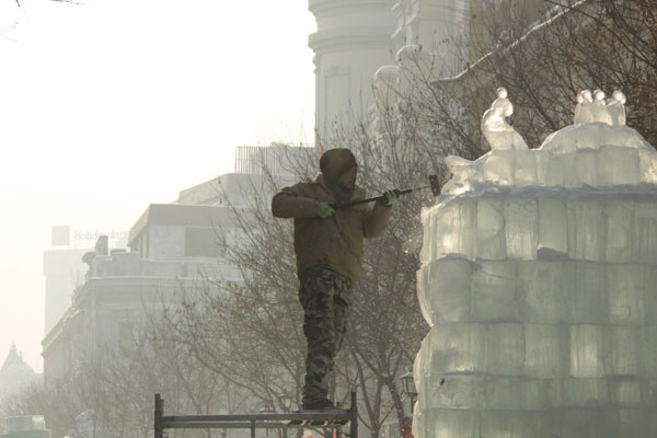 An ice sculptor carves a block of ice on Central Street in Harbin, northeast China's Heilongjiang Province, on December 18, 2012. (CRIENGLISH.com)