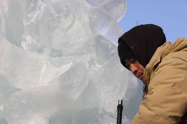 An ice sculptor carves a block of ice on Central Street in Harbin, northeast China's Heilongjiang Province, on December 18, 2012. (CRIENGLISH.com)