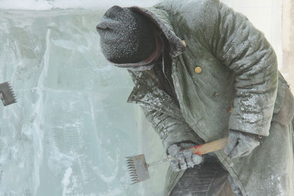 An ice sculptor carves a block of ice on Central Street in Harbin, northeast China's Heilongjiang Province, on December 18, 2012. (CRIENGLISH.com)