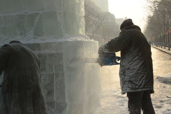 Ice sculptors carve a block of ice on Central Street in Harbin, northeast China's Heilongjiang Province, on December 18, 2012. (CRIENGLISH.com)